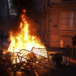 Un hombre pasa frente a una pared iluminada por una barricada en llamas en la que está escrito "La policía mata" en el centro de Lyon, en el centro de Francia, el viernes 30 de junio de 2023.