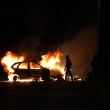 Manifestantes pasan junto a un coche en llamas durante los enfrentamientos con la policía en Le Port, en la isla francesa de La Reunión, en el océano Índico, el 30 de junio de 2023, tres días después de que un joven de 17 años recibiera un disparo en el pecho a quemarropa por parte de la policía en Nanterre, un suburbio del oeste de París