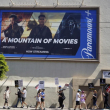Un anuncio del servicio de transmisión Paramount+ aparece arriba de escritores y actores en huelga en un mitin frente a los estudios Paramount en Los Ángeles el viernes 14 de julio de 2023.