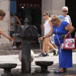 Mujeres se refrescan del grifo de una fuente pública en Madrid