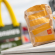 Una bolsa para llevar de McDonald's y un puesto de vasos para llevar que la acompaña frente a una sucursal de McDonald's.