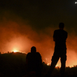 La gente observa los incendios cerca del pueblo de Malona en la isla griega de Rodas el 23 de julio de 2023. Decenas de miles de personas huyeron de los incendios forestales en la isla griega de Rodas el 23 de julio de 2023, mientras los turistas aterrorizados se apresuraban a llegar a casa.