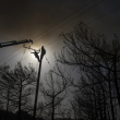 Un trabajador sube a un puesto eléctrico para reparar cables tras un incendio en la localidad de Gennadi