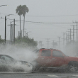 Los vehículos salpican agua durante las fuertes lluvias del huracán Hilary