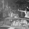 Fotografía de María de los Ángeles Trujillo Martínez, Angelita, durante el desfile de la Feria de la Paz. Se observa vestida con un traje blanco de corte militar, saludando la multitud desde un auto convertible, en la avenida George Washington.