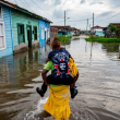 Un hombre carga a una mujer en su espalda mientras camina por el agua en un área inundada de Batabano