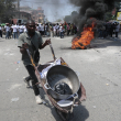 Un hombre empuja una carretilla entre neumáticos incendiados por manifestantes durante una protesta contra la inseguridad en Puerto Príncipe, Haití