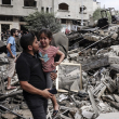 Un hombre lleva a un niño llorando mientras camina frente a un edificio destruido en un ataque aéreo israelí en la ciudad de Gaza el 7 de octubre de 2023