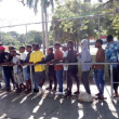 Haitianos hacen turno en una fila para someterse al registro de datos biométricos