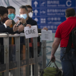 personas con mascarilla esperan en la zona de llegada de pasajeros del aeropuerto internacional Beijing Capital