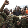 A la izquierda, Guy Philippe, el exlíder militar golpista haitiano que el pasado sábado anunció su intención de entrar con sus fuerzas a la capital, Puerto Príncipe, con planes de derrocar al gobierno.