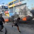 La gente pasa junto a neumáticos en llamas durante una manifestación que pide la salida del primer ministro haitiano Ariel Henry en Puerto Príncipe el 6 de febrero de 2024. El gobierno de Haití anunció el 5 de febrero de 2024 una ofensiva contra la agencia paramilitar y ambiental. Brigada de Seguridad de Áreas Protegidas (BSAP), cuyos agentes fuertemente armados han ganado poder recientemente y han sido culpados de violentos enfrentamientos con la policía la semana pasada.