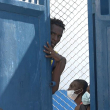 Esta captura de pantalla tomada de AFPTV muestra a una persona mirando desde detrás de una puerta cerca de la prisión principal de Puerto Príncipe, Haití