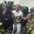 Esta foto difundida por la Policía ecuatoriana muestra a Jorge Glas escoltado por miembros del Grupo Especial de Acción Penitenciaria (GEAP) durante su llegada a la prisión de máxima seguridad La Roca en Guayaquil
