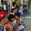 Algunas personas esperaban afuera de la biblioteca, sentados, llenando un formulario para aplicar a una de las 88 vacantes disponibles.