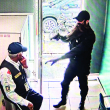 Un hombre participante en el robo a mano armada en una sucursal del Banco Popular apunta su arma a un guardia de seguridad, antes del escape con el botín.