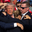 Donald Trump, con el lado derecho de su rostro ensangrentado, es rodeado por su seguridad mientras levanta su puño ante la multitud después del atentado en su contra.