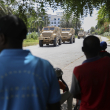 Los residentes observan vehículos blindados que transportan a agentes de policía de Kenia que forman parte de una fuerza multinacional respaldada por la ONU en Puerto Príncipe, Haití, el miércoles 17 de julio de 2024.