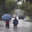 La gente se adentra en las aguas de la inundación que superan Gordon Street mientras continúa lloviendo debido a la tormenta tropical Debby, el martes 6 de agosto de 2024, en Charleston, Carolina del Sur.