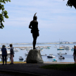 Unos visitantes se encuentran cerca de una estatua de 1921 del líder Wampanoag Massasoit, al centro, el miércoles, 9 de junio de 2021, en Cole's Hill, en Plymouth, Massachusetts