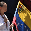 La líder de la oposición venezolana, María Corina Machado, sostiene una bandera nacional venezolana mientras hace un gesto desde lo alto de un camión durante una manifestación para protestar por los resultados de las elecciones presidenciales, en Caracas, el 3 de agosto de 2024.