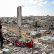 Un hombre parado en lo alto de un edificio muy dañado ve otros edificios destruidos en Khan Yunis, en el sur de la Franja de Gaza. Foto de Bashar TALEB