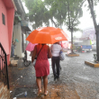 Varias personas se desplazan por una acera inundada del Distrito Nacional