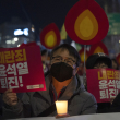 Un manifestante sostiene un cartel con la leyenda "Renuncia, Yoon Suk Yeol" mientras se une a otros en una marcha hacia la oficina presidencial después de una vigilia con velas contra el presidente surcoreano Yoon Suk Yeol, en Seúl, Corea del Sur, el miércoles 4 de diciembre de 2024 (Foto AP/Ng Han Guan)