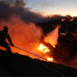 Un bombero apaga las llamas mientras un helicóptero arroja agua alrededor de las casas amenazadas por el incendio Palisades impulsado por el viento en Pacific Palisades, California, 7 de enero de 2025.