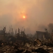 El sol brilla a través del humo sobre las ruinas de las casas del incendio forestal.