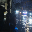 Personas se refugian de las inundaciones en un negocio, mientras varios vehículos se desplazan por una calle