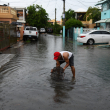 Un hombre saca de entre el agua pertenencias personales arrastradas por los aguaceros.
