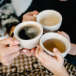 Manos sosteniendo tazas de café y té por la mañana.