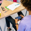 Imagen ilustra a un niño usando un celular en la escuela.