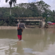 Un hombre cruza el río Camú, luego que las lluvias hicieran colapsar el puente