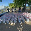 Imágen del cargamento decomisado de supuesta cocaína junto a los hombres que fueron arrestados por portarla en una narcolancha.