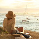 Fotografía muestra mujer disfrutanto del sol y la playa.