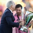 Lionel Messi, del Inter Miami, sostiene el trofeo de campeón de la MLS y recibe un beso de Jorge Mas, dueño del equipo, tras la victroia ante Vancouver.