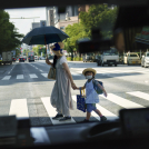 Una mujer cruza la calle con un niño, vista a través de la ventana de un taxi en Tokio el lunes 19 de julio de 2021.