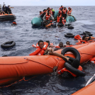 Migrantes que viajaban en una lancha de goma caen al agua mientras otros se aferran a una boya antes de ser rescatados por un equipo del barco Sea Watch-3, a unas 35 millas de la costa Libia, el lunes 18 de octubre de 2021.