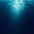 Bucle perfectamente transparente de olas del océano azul profundo desde el fondo submarino, rayos de luz brillando a través.