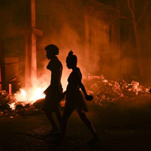 Personas pasan junto a una hoguera encendida por los manifestantes durante una protesta contra la falta de energía en el barrio de Lawton, en La Habana, el 14 de mayo de 2026
