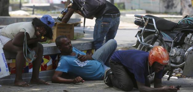 Varias personas se refugian de los disparos durante choques entre la policía y bandas armadas en las inmediaciones del Palacio Nacional, en Puerto Príncipe, Haití, el 8 de abril de 2024
