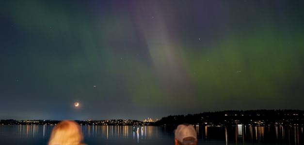 Un grupo de personas admira la aurora boreal que ilumina el lago Washington