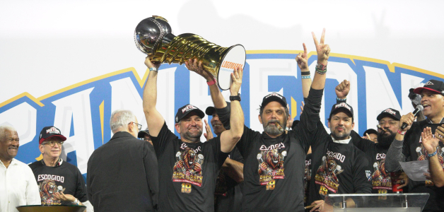 Eduardo Najri y José Miguel Bonetti, principales ejecutivos del Escogido, levantan la copa de campeón del pasado torneo.