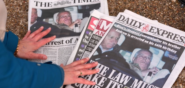 Una reportera observa las portadas de la prensa británica el 20 de febrero de 2026 de 2026, tras el arresto durante unas horas del Andrew Mountbatten-Windsor, hermano del rey Carlos III de Inglaterra.