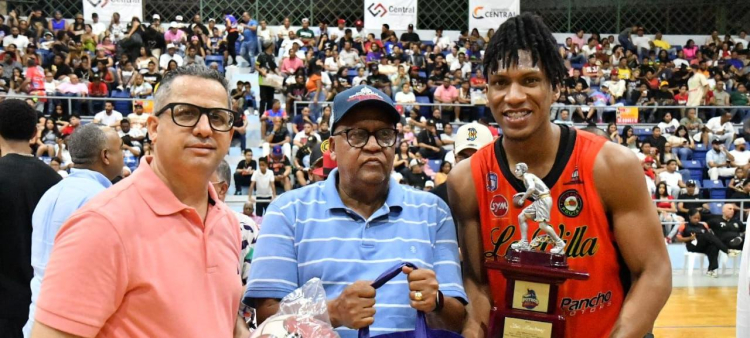 El jugador más valioso del torneo superior de La Vega, Luis Martínez, del club La Villa, recibe su trofeo y regalos de manos de José Luis Bautista y Frank García.