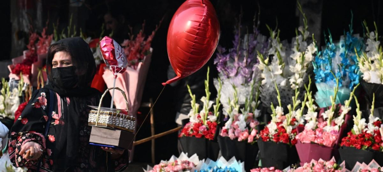 Una mujer sostiene un globo con forma de corazón mientras camina por una calle el día de San Valentín en Lahore el 14 de febrero de 2026. (Foto de Arif ALI / AFP)