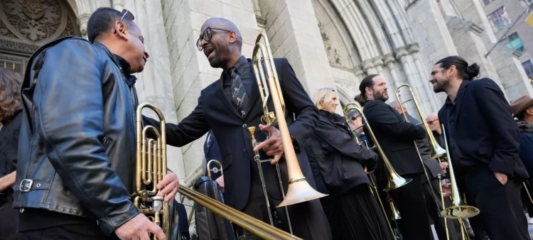 Un grupo de músicos, principalmente trombonistas, socializan y posan para calentar antes de tocar en el funeral de Willie Colón en la Catedral de San Patricio en Nueva York, el lunes 9 de marzo de 2026.