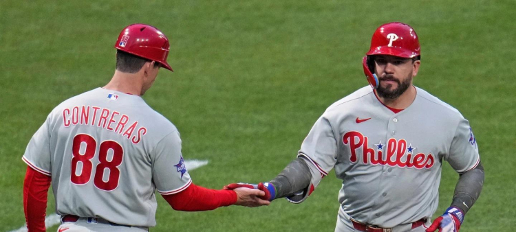 Kyle Schwarber, de los Filis, es felicitado por el coach de tercera de los Filis tras su segundo vuelacercas en el juego.